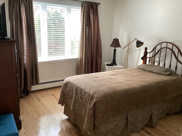 bedroom with light hardwood / wood-style flooring and a baseboard heating unit