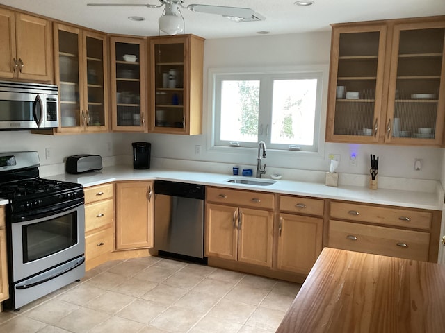 kitchen with sink, light tile patterned floors, ceiling fan, and appliances with stainless steel finishes