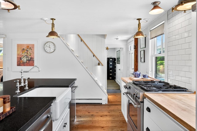 7 Anthony St, Provincetown, MA 02657 - kitchen featuring appliances with stainless steel finishes, light wood-style flooring, a baseboard radiator, white cabinets, and wood counters