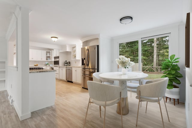 dining space with light hardwood / wood-style flooring and ornamental molding