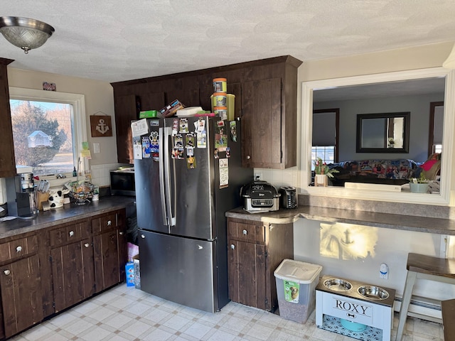 kitchen featuring a baseboard radiator, a textured ceiling, dark brown cabinetry, and stainless steel refrigerator