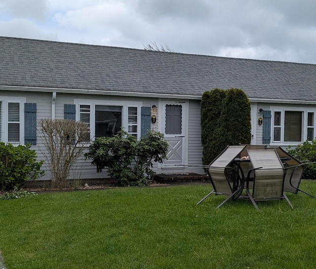 rear view of property featuring a yard and roof with shingles