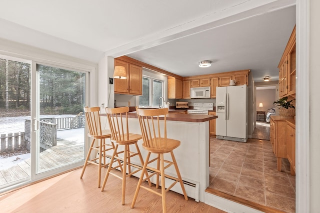 kitchen with white appliances, a breakfast bar, kitchen peninsula, and sink