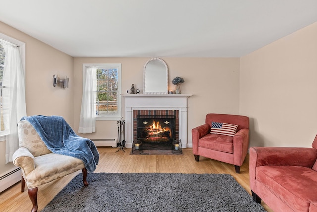 living room with hardwood / wood-style flooring, a baseboard radiator, and a fireplace