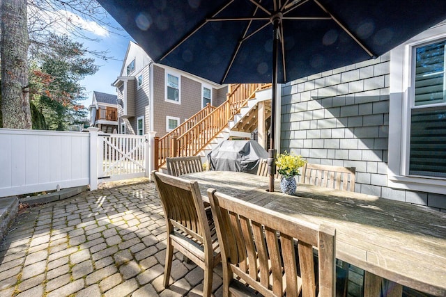 view of patio / terrace featuring stairway, outdoor dining area, fence, and a gate