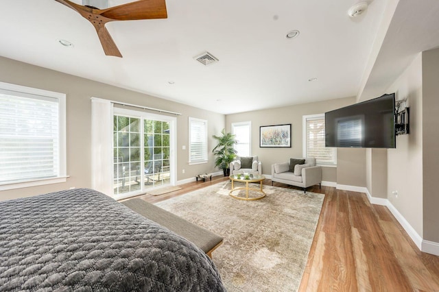 bedroom featuring baseboards, multiple windows, visible vents, and wood finished floors