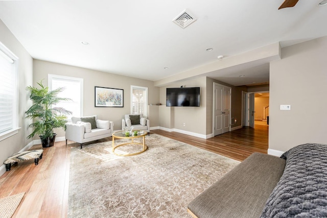 living area with visible vents, baseboards, and wood finished floors