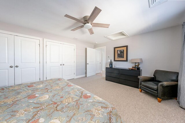 carpeted bedroom with attic access, visible vents, multiple closets, and a ceiling fan