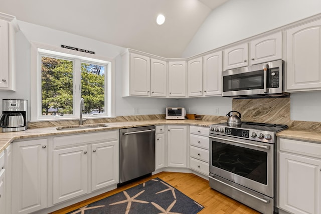74 Deering Dr, Chatham, MA 02633 - kitchen featuring stainless steel appliances, vaulted ceiling, light wood-type flooring, white cabinetry, and recessed lighting