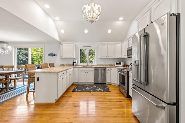 74 Deering Dr, Chatham, MA 02633 - kitchen featuring stainless steel appliances, a chandelier, a peninsula, vaulted ceiling, and plenty of natural light