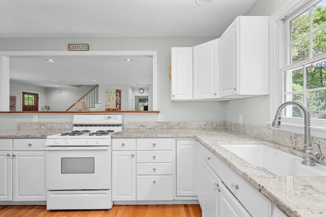 2 Julie Ln, Cotuit, MA 02635 - kitchen featuring white range with gas stovetop, white cabinetry, light wood finished floors, recessed lighting, and light stone counters