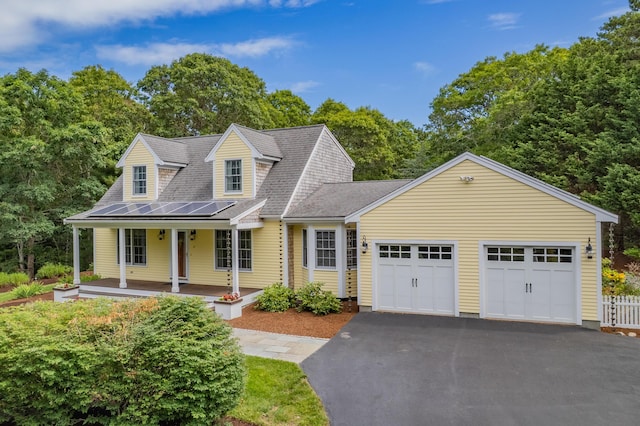 2 Julie Ln, Cotuit, MA 02635 - new england style home with asphalt driveway, a garage, solar panels, a porch, and a shingled roof