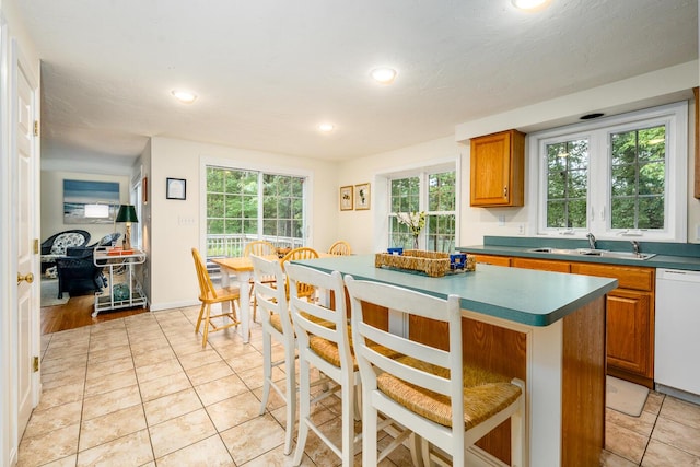 kitchen featuring light tile patterned flooring, a center island, a wealth of natural light, and dishwasher