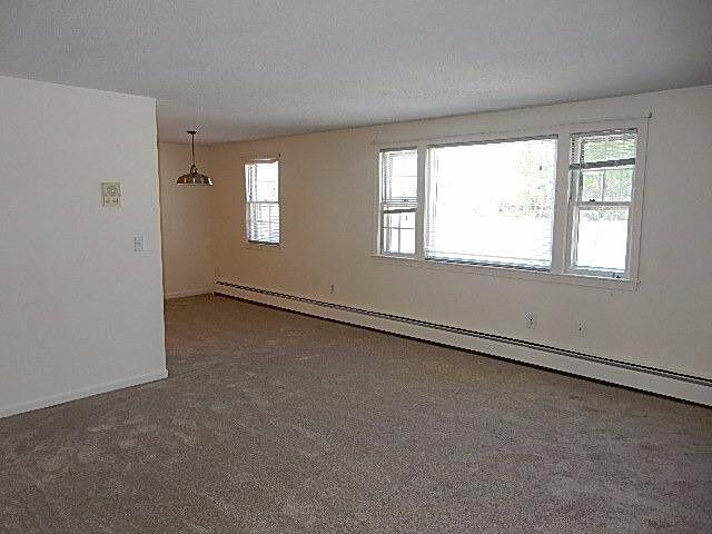 carpeted spare room featuring a textured ceiling and baseboard heating