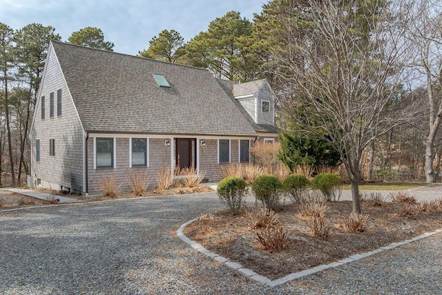 cape cod-style house featuring gravel driveway and a shingled roof