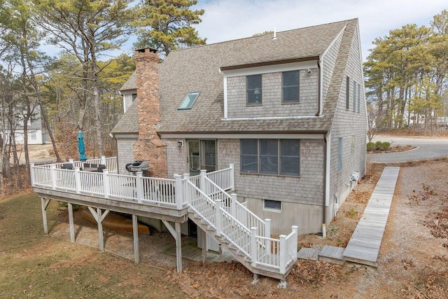 rear view of house featuring stairway, roof with shingles, a chimney, and a wooden deck