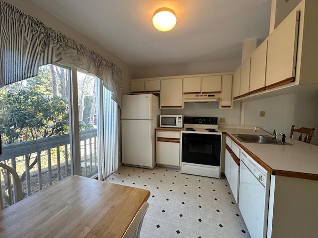 kitchen with white appliances, light floors, light countertops, under cabinet range hood, and a sink