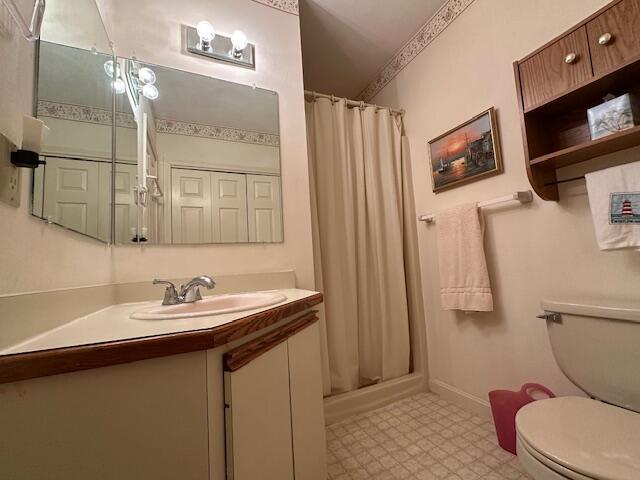 bathroom featuring curtained shower, toilet, and tile patterned floors