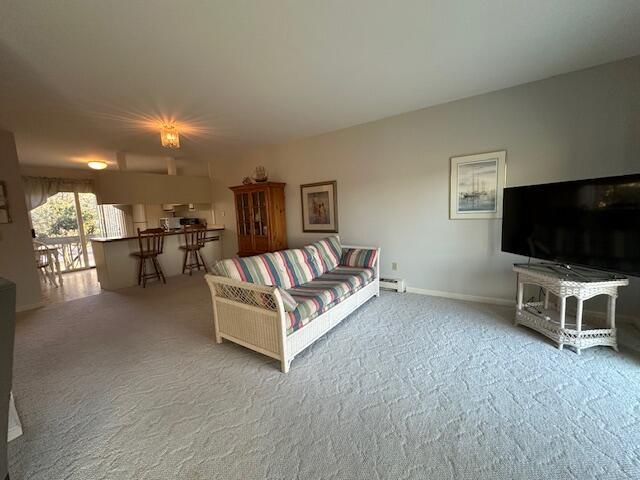 carpeted living room with a baseboard heating unit and baseboards