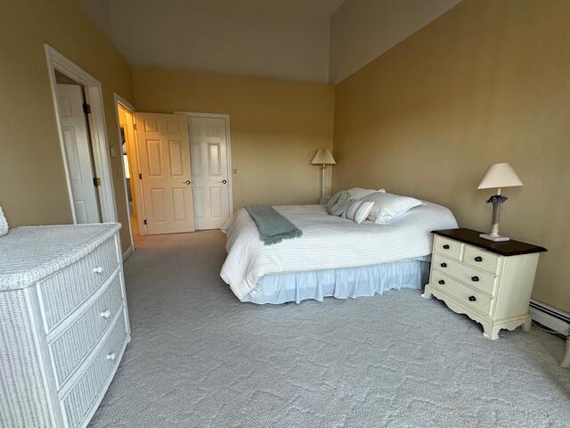 bedroom with a baseboard heating unit and carpet flooring