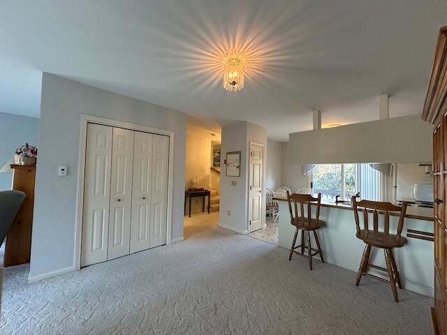 kitchen with light carpet, baseboards, and a kitchen breakfast bar