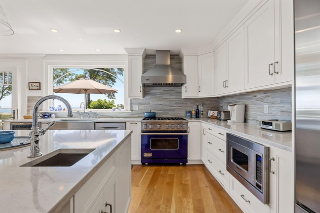 30 Tisquantum Rd, Chatham, MA 02633 - kitchen featuring premium appliances, wall chimney range hood, light wood finished floors, backsplash, and light stone countertops