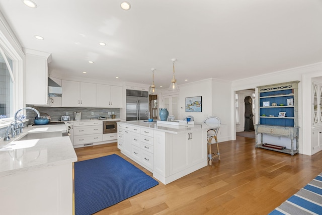 30 Tisquantum Rd, Chatham, MA 02633 - kitchen with appliances with stainless steel finishes, ornamental molding, backsplash, white cabinets, and wall chimney range hood