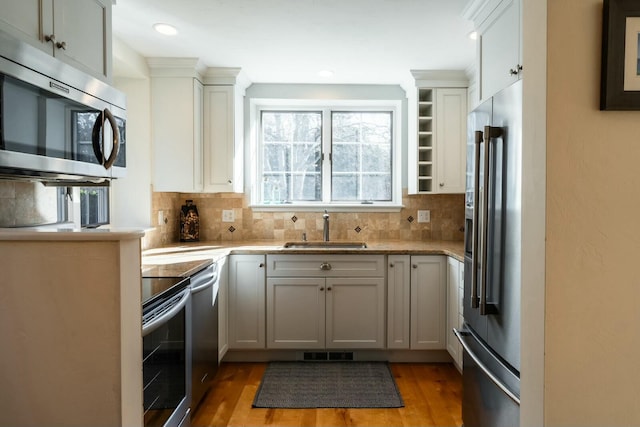 kitchen featuring stainless steel appliances, a sink, white cabinets, dark wood-style floors, and open shelves
