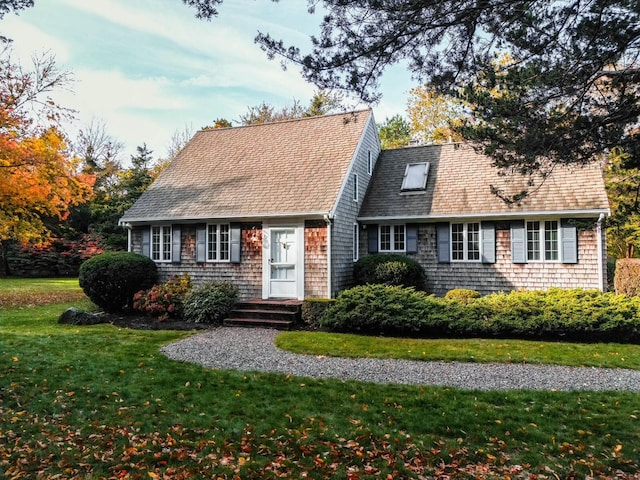 new england style home with roof with shingles and a front yard