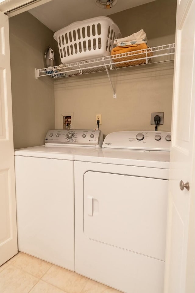 clothes washing area featuring light tile patterned floors, laundry area, and washing machine and dryer