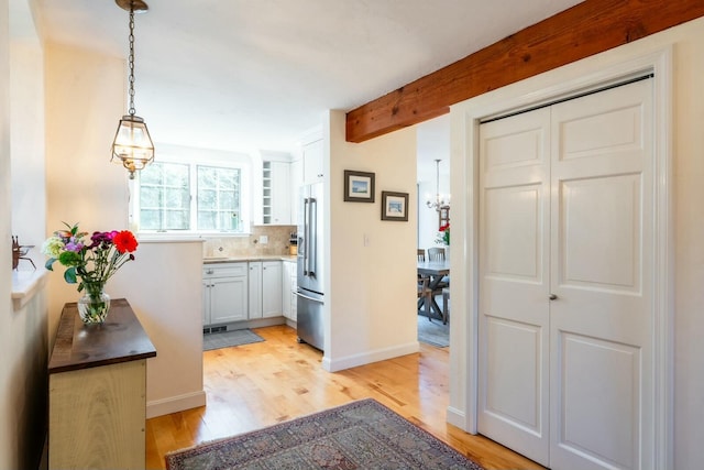 hallway with light wood-style floors, baseboards, and beamed ceiling