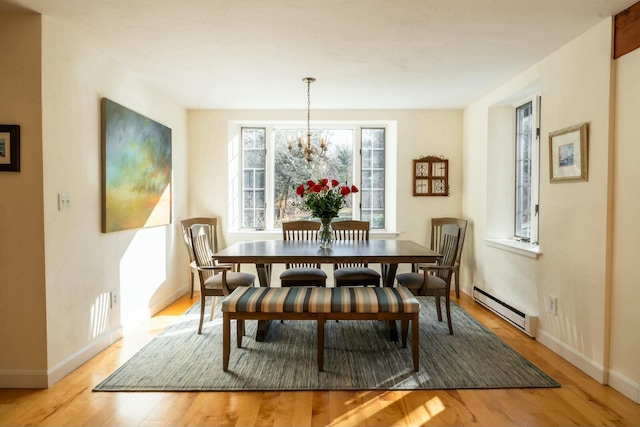 dining room with light wood-type flooring, baseboards, baseboard heating, and a notable chandelier