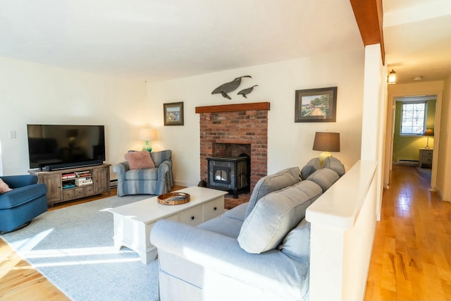 living room with a wood stove, a baseboard radiator, and wood finished floors