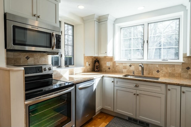 kitchen featuring stainless steel appliances, backsplash, a sink, and visible vents