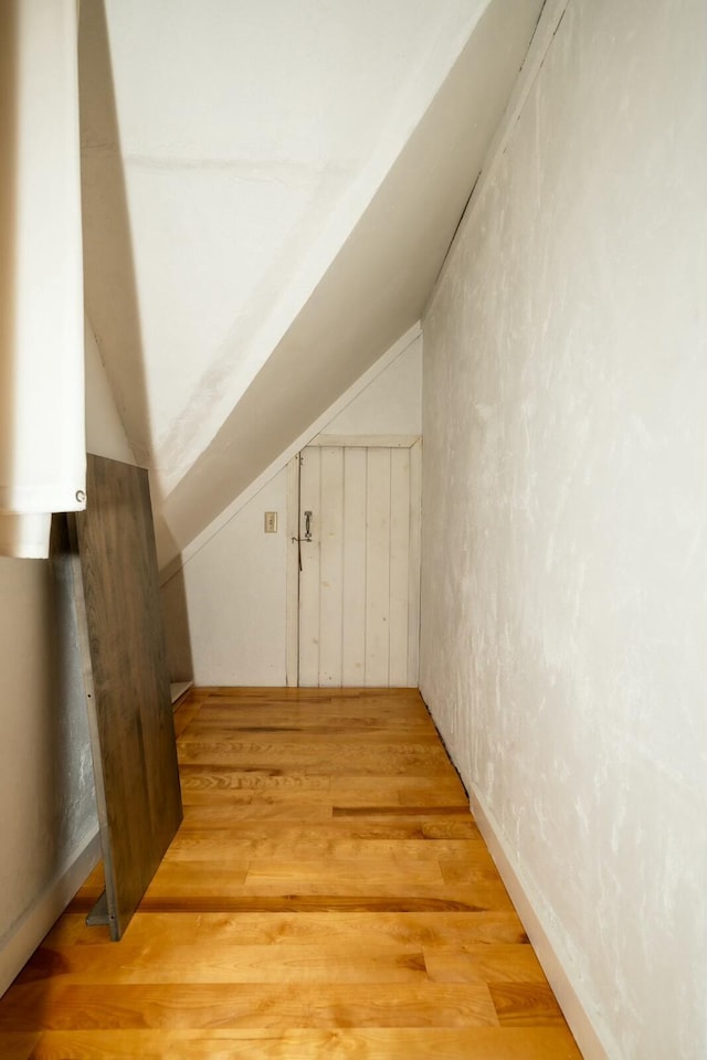 bonus room with light wood finished floors and vaulted ceiling