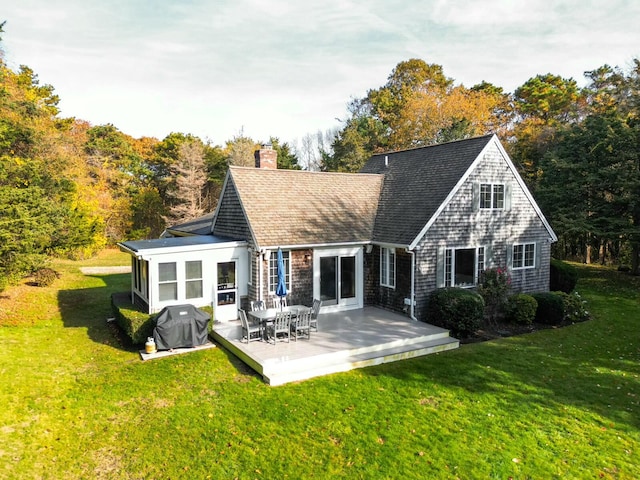 back of house featuring roof with shingles, a lawn, and a chimney