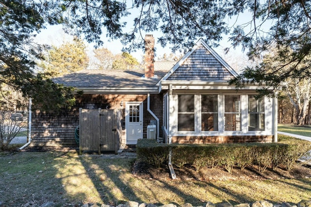 view of front of property with a front yard, a sunroom, roof with shingles, and a chimney