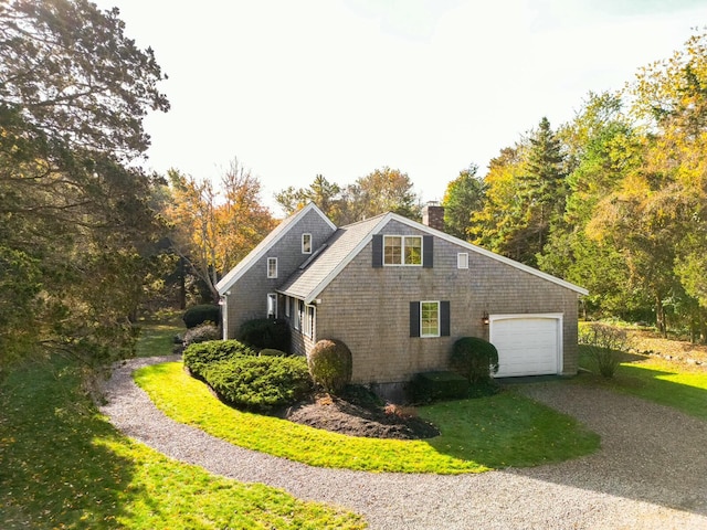 view of side of home featuring a garage, a yard, a chimney, and gravel driveway