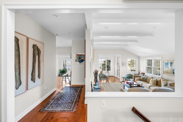 hallway with baseboards, wood-type flooring, and vaulted ceiling with beams