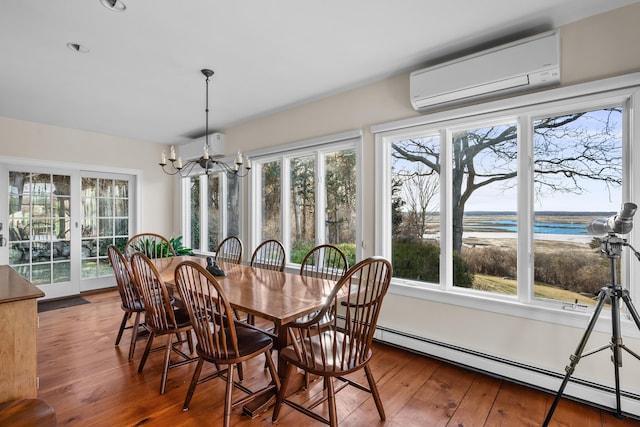 dining area with a baseboard heating unit, wood-type flooring, a notable chandelier, and a wall mounted AC