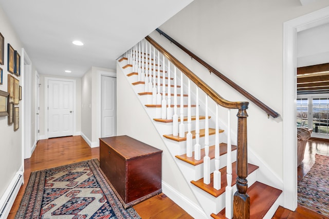 stairs with a baseboard heating unit, wood finished floors, and baseboards