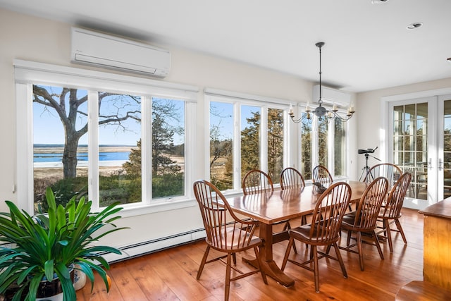 dining room with a chandelier, a wall unit AC, baseboard heating, french doors, and hardwood / wood-style flooring