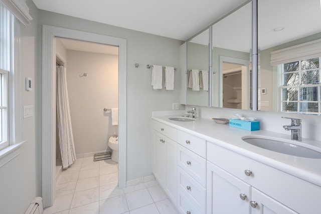 bathroom with double vanity, a baseboard heating unit, baseboards, and a sink