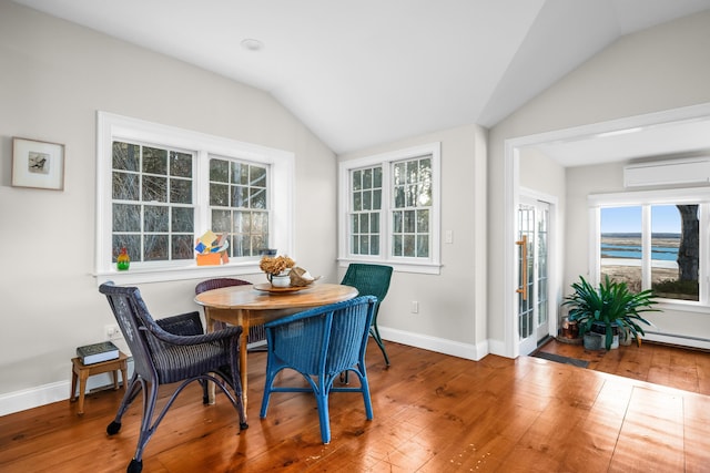 dining space with an AC wall unit, hardwood / wood-style flooring, plenty of natural light, and lofted ceiling