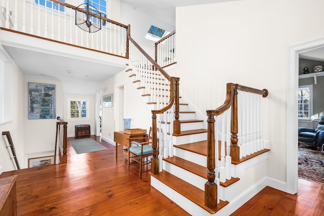 staircase with a high ceiling, baseboards, and wood-type flooring