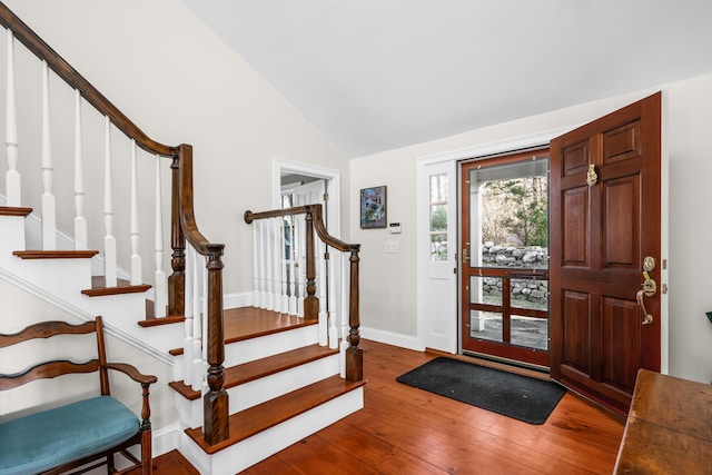 entryway featuring baseboards, wood-type flooring, stairs, and vaulted ceiling