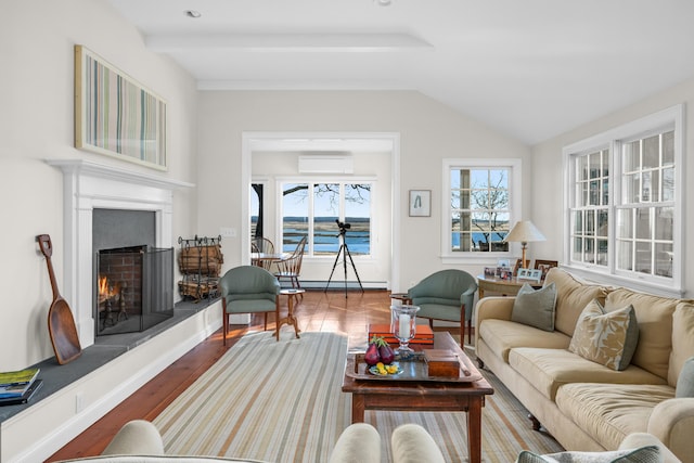 living area with wood finished floors, a wall unit AC, a lit fireplace, a baseboard radiator, and vaulted ceiling