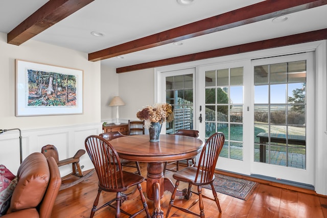 dining room featuring hardwood / wood-style floors, beamed ceiling, recessed lighting, and a wainscoted wall