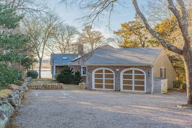 view of front of home featuring a garage, a chimney, and a shingled roof