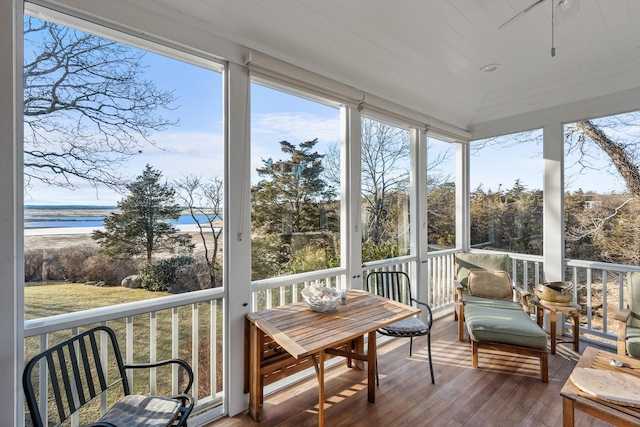 sunroom with vaulted ceiling and a water view